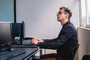 An office worker working on his computer in the office. Smart worker at he desk computer. Programmer doing his work with many computers. High quality photo