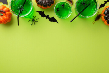Halloween concept. Top view photo of glasses with green swamp punch spiders bat silhouettes...