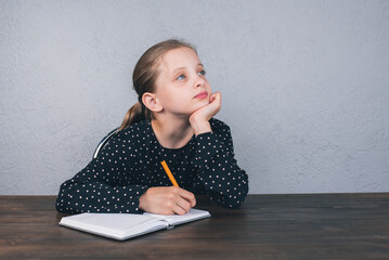 A European girl is sitting at the table doing her homework. Studies. Homework.