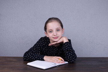 Naklejka premium European girl sitting at the table and doing homework. Portrait of a beautiful girl.