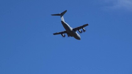 Royal Air Force Airbus A400M Atlas military plane (RAF ZM414) flying low level dropping 3 PARA parachute regiment soldiers on an airborne assault military exercise, summer bright cloud sky