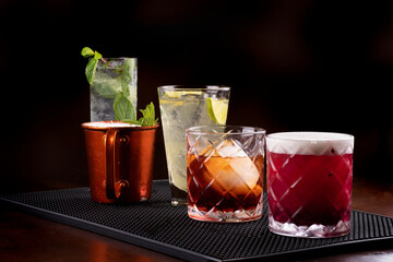 cocktail collection in professional rubber holder with negroni mule mojito soda dark background