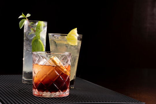 cocktails professionally presented on pub counter dark background Negroni and mojito