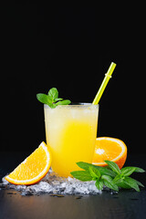 Glass of fresh orange juice with ice on a black background 