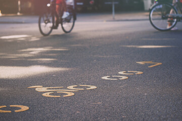 crowded inner city junction with modern bicycle route symbols painted in orange on asphalt....