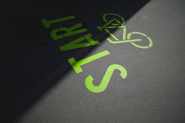 green bicycle symbol with lettering start painted on inner city asphalt surface. urban mobility and sport motivation concept. slogan for ecological traffic turn. selective focus.