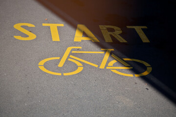 bicycle symbol with lettering start painted in traffic yellow on inner city asphalt surface. urban...