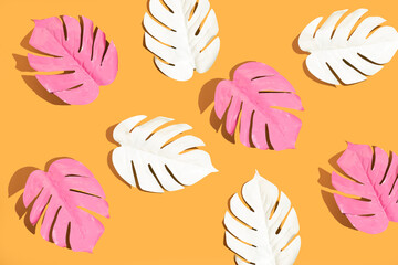 Fototapeta na wymiar White and pink monstera leaves on yellow background. Minimal summer concept. Flat lay