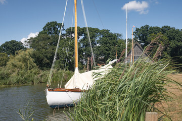 The front end or bow of a traditional sailing boat moored against the wooden quay heading
