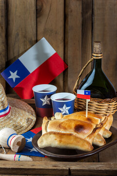 Chilean independence day concept. fiestas patrias. Tipical baked empanadas de pino, wine or chicha, hat and play emboque. Dish and drink on 18 September party, wooden background