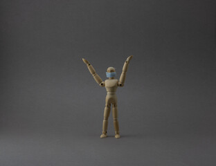 Wooden mannequin with protective surgical mask in grey backgound