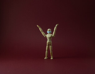 Wooden mannequin with protective surgical mask in purple backgound