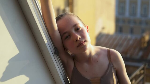 portrait of a girl ballerina in the window of the house
