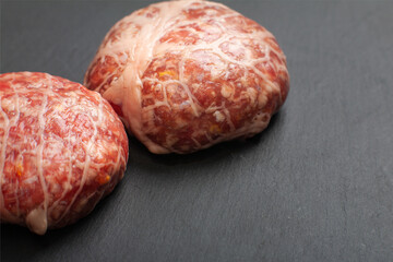 minced meat cutlets in a thin fatty mesh shell is ready for use, semi-finished products in a fat grid, copy space.