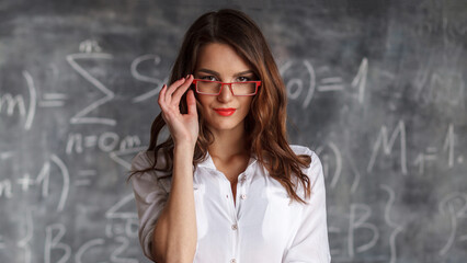 smart beautiful woman in glasses near blackboard with math calculations