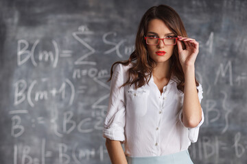 smart attractive woman in glasses near blackboard with math calculations