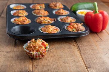 vegetable muffins in a baking form with pepper, corn and zucchini, focus on foreground