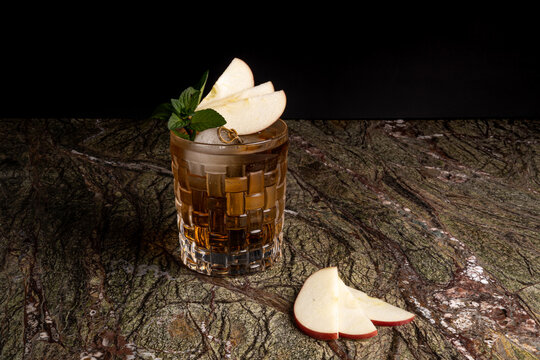C&oacute;ctel sobre fondo negro en un bar con garnitura de manzana mezcal tequila bar vodka wiskey tonic 