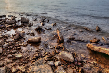 Obraz premium Long exposure of Rocks and sand on the bank of a lake