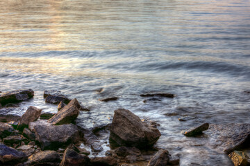 Long exposure of Rocks and sand on the bank of a lake