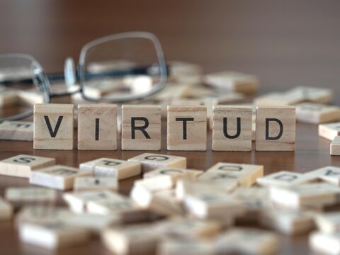 virtud palabra o concepto representado por baldosas de letras de madera sobre una mesa de madera con gafas y un libro