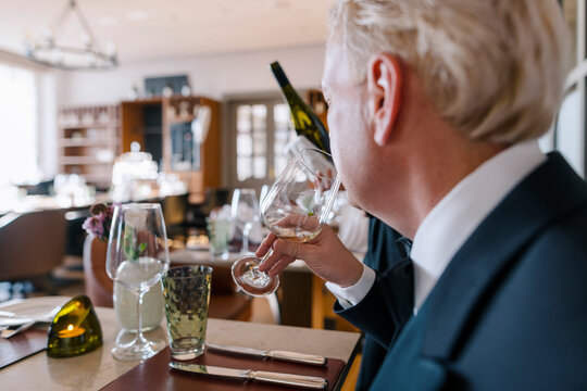 Eine Kellnerin hat einem Gast im Smoking im Restaurant des Steigenberger Grand Hotel Petersberg in Königswinter bei Bonn eine Weinprobe eingeschenkt, die er kostet. 