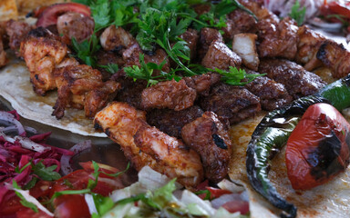 Close up Mixed Turkish kebab including meat and chicken with vegetables pepper tomato onion parsley. Selective focus of area.