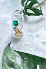 Various serum capsules for healthy skin routine. Anti-wrinkle rejuvenation skin treatment. Beauty product presentation. Off white stone marble background with monstera leaf.