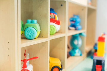 Different kinds of colorful plastic and plush toys on the shelves in the playroom at the nursery school. Learning through play. High quality photo
