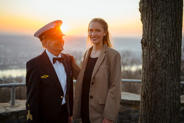 Ein deutscher Marinesoldat steht mit einer jungen, blonden Frau an einem alten Baum im Abendrot. Er...