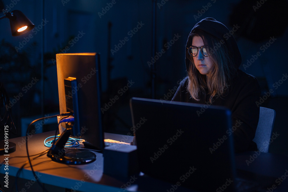 Poster cybercrime, hacking and technology concept - female hacker in dark room writing code or using comput