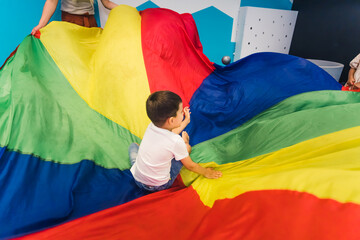 Happy toddlers having an active sensory play with texture and colors at the nursery school. Kids wellness. Early fine motor and gross motor skills development. Healthy brain. High quality photo