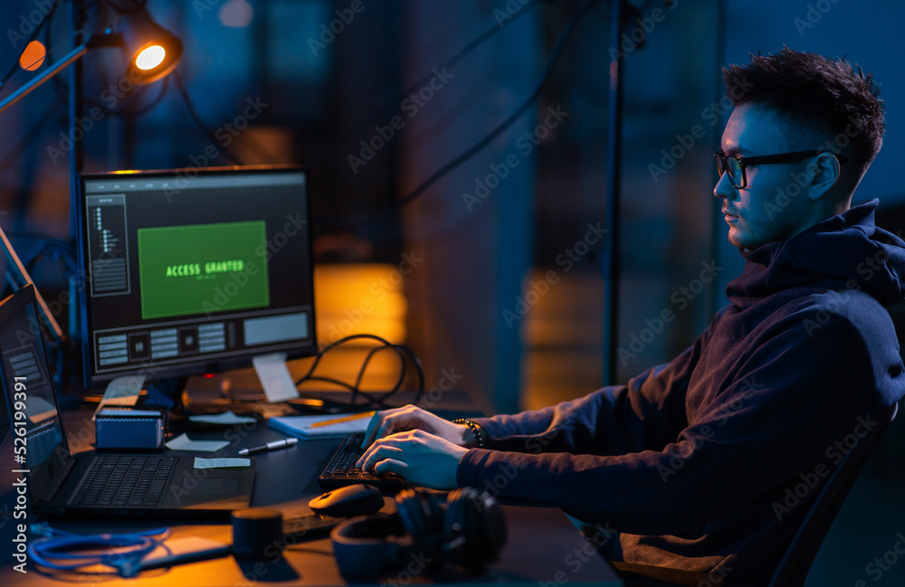 Poster cybercrime, hacking and technology concept - male hacker in dark room writing code or using computer