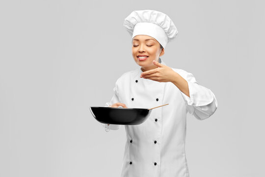 Cooking, Culinary And People Concept - Happy Smiling Female Chef With Frying Pan Smelling Food Over Grey Background