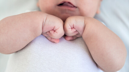 Close up of newborn boy hand on white sheet background. Baby sleeping on the bed