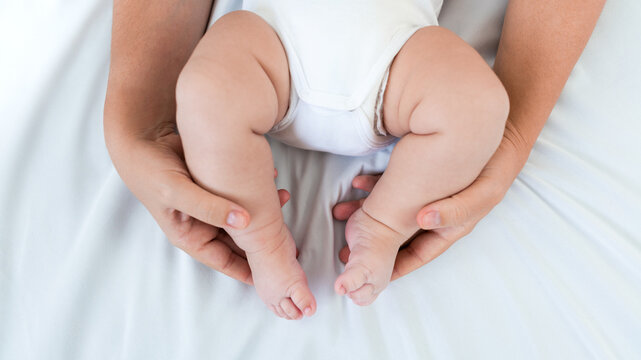 Mom hands holding newborn legs. Beautiful conceptual image motherhood and baby