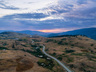 Aerial View of a Scenic Road in the Desert during colorful cloudy sunrise. Near Vernon, Okanagan,...