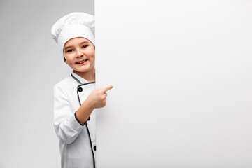 cooking, culinary and profession concept - happy smiling little boy in chef's toque and jacket showing white board over grey background
