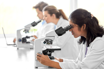 science research, work and people concept - international team of scientists with microscopes...