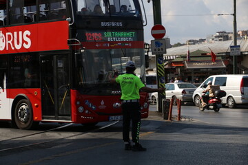 The traffic police in Istanbul Eminönü determines the road routes of the vehicles and prevents the formation of traffic. Traffic police gave way to tourists' red sightseeing bus in Eminönü