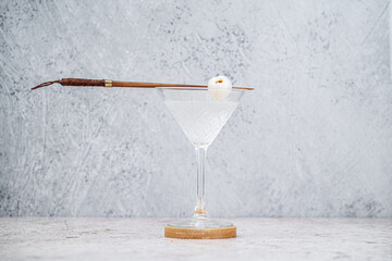 Coctel Martini de Litchi en copa sobre fondo de concreto. Enfoque selectivo. Profundidad...