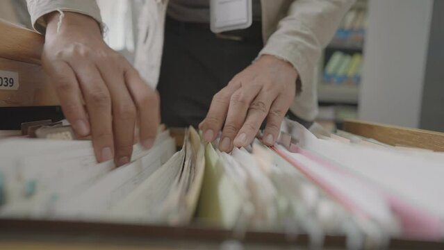 Hands of a business man searching for documents in a filing cabinet at the office.