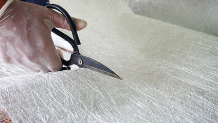 Fiberglass material cutting by scissors. close up view