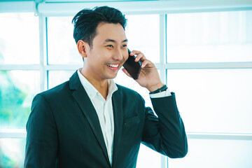 Handsome asian man using smartphone while walking at airport terminal, young asian man browsing mobile internet on cellphone while going to flight boarding, side view