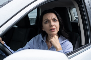 A very surprised and interested woman is listening to someone from her car.