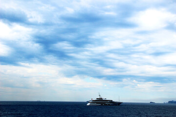 Perfect view in Amalfi coast with a technological boat slightly rippling the deep blue Tyrrhenian sea, a few mountains in the background and a fantastic varied sky full of imposing white clouds