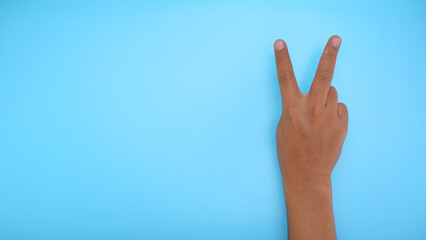 Male hand showing hand two sign isolated on blue background 