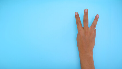 Male hand showing hand three sign isolated on blue background 