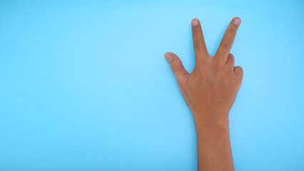 Male hand showing hand three sign isolated on blue background 