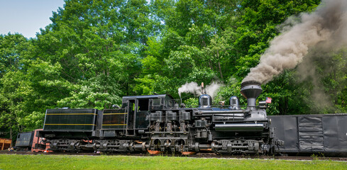 A View of an Antique Shay Steam Engine Warming Up, Blowing Smoke and Steam on a Sunny Day